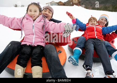 I genitori e i bambini Equitazione sulla neve gonfiabile tubo Foto Stock