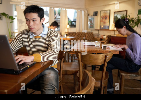 Giovane uomo seduto nella caffetteria sul computer portatile Foto Stock