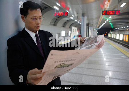 Imprenditore quotidiano di lettura in una stazione ferroviaria Foto Stock