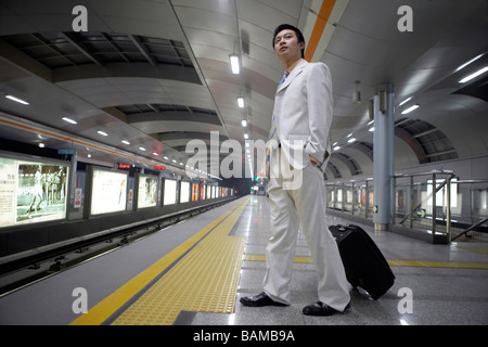 Maschio cinese attende pazientemente che il treno della metropolitana per arrivare Foto Stock