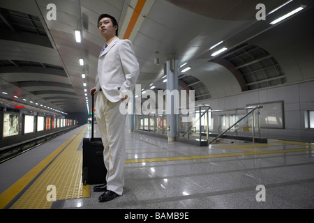 Maschio cinese attende pazientemente che il treno della metropolitana per arrivare Foto Stock