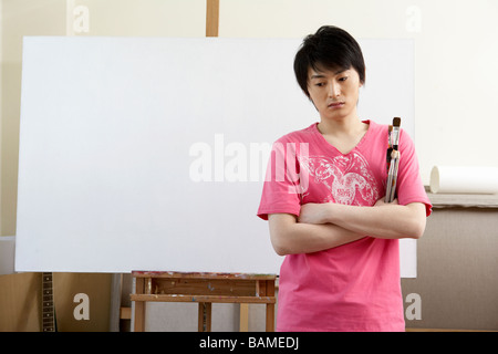 Giovane uomo che appare frustrato di fronte ad un vuoto di tela di arte Foto Stock