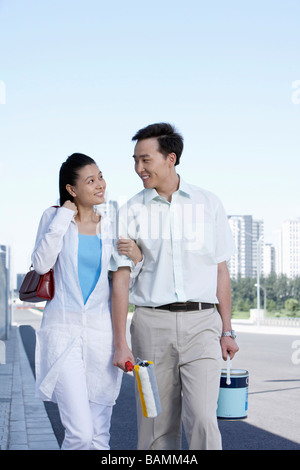 L uomo e la donna bracci di collegamento, passeggiate e sorridente ad ogni altro Foto Stock