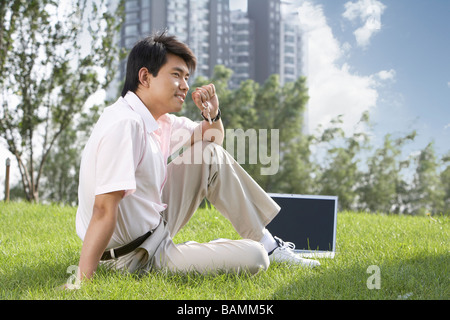 Uomo seduto in un parco con un laptop Foto Stock