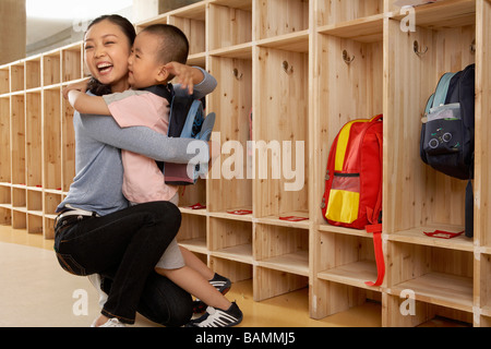 La madre abbraccia il figlio a scuola Foto Stock