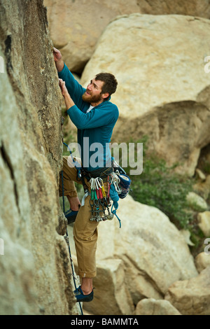 Scalatore risale una ripida roccia sporgente a Joshua Tree National Park California Foto Stock