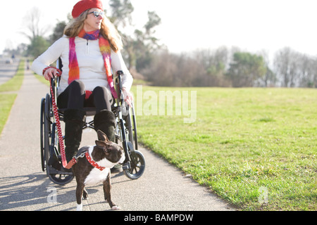 Donna in carrozzella assumendo il suo cane per una passeggiata Foto Stock