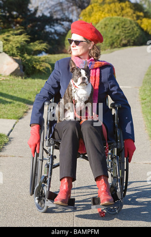 La donna in sedia a rotelle con il cane sul suo giro Foto Stock