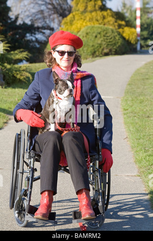 La donna in sedia a rotelle con il cane sul suo giro Foto Stock