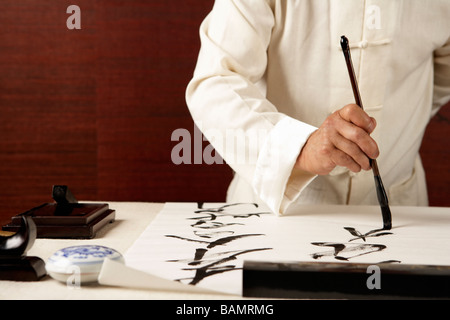 Uomo anziano praticare la calligrafia Foto Stock