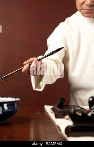 Uomo anziano praticare la calligrafia Foto Stock
