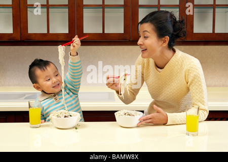 Madre e figlio mangiare tagliatelle insieme Foto Stock