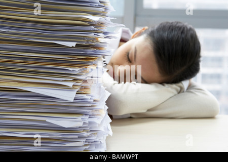 Imprenditrice dormire accanto al mucchio di lavoro Foto Stock