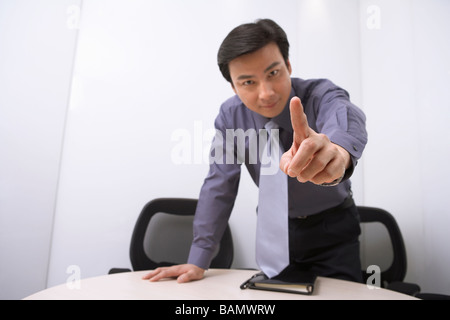 Imprenditore puntando alla fotocamera, sorridente Foto Stock