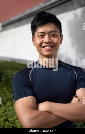 Atleta sorridente e piega le braccia Foto Stock