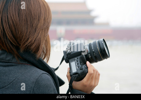 Giovane donna tenere la fotocamera si affaccia a Piazza Tiananmen, Pechino, Cina Foto Stock