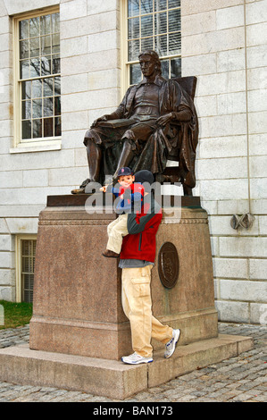 Padre sollevando il suo figlio a toccare il John Harvard statua presso la Harvard University di Cambridge, Massachusetts, STATI UNITI D'AMERICA Foto Stock