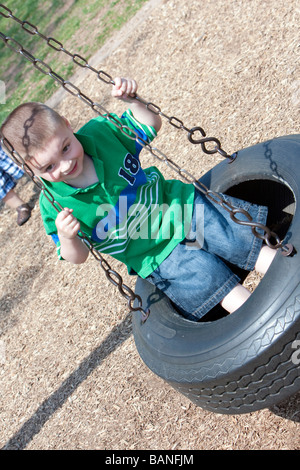 A quattro anni di vecchio ragazzo su un parco pneumatici swing. Foto Stock