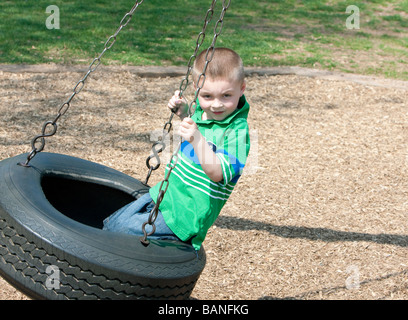 A quattro anni di vecchio ragazzo su un parco pneumatici swing. Foto Stock