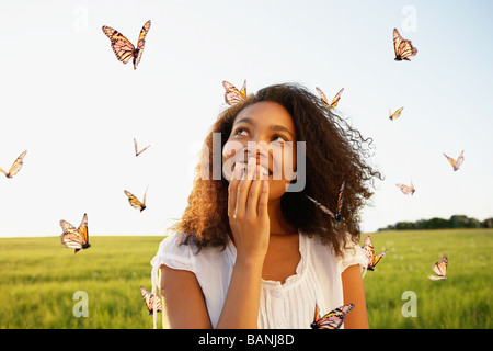 Donna africana in piedi tra le farfalle in Prato Foto Stock