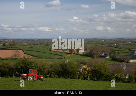 Coltivatore su un trattore lo spandimento di fertilizzante su campi nel paesaggio rurale della contea di Tyrone Irlanda del Nord Regno Unito Foto Stock