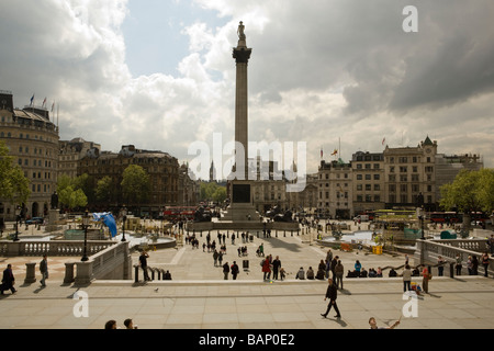 Nelson la colonna con i turisti in Trafalgar Square, Londra e nuvole temporalesche tettuccio Foto Stock