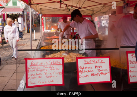 Il cibo caldo compreso paella e tartiflette per la vendita su un mercato francese stallo in Norwich, Norfolk, Regno Unito Foto Stock