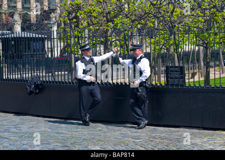 La piazza del Parlamento , Westminster , due metropolitan armati poliziotti in uniforme di stare in guardia in sole fuori House of Commons Foto Stock