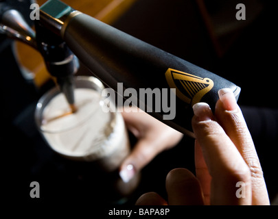 Una pinta di Guinness è versata in un pub Foto Stock