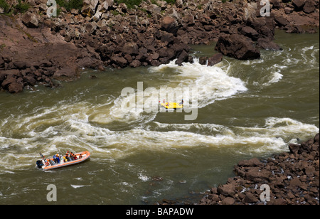 I turisti rafting delle acque bianche sul Fiume pericolose rapide nel Parco Nazionale di Iguazu confine Brasile e Argentina recovery power boat in primo piano per la sicurezza Foto Stock