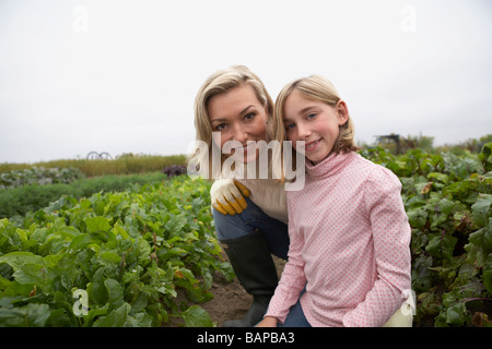 Madre e figlia insieme in ginocchio in orto biologico, Ladner, British Columbia, Canada Foto Stock