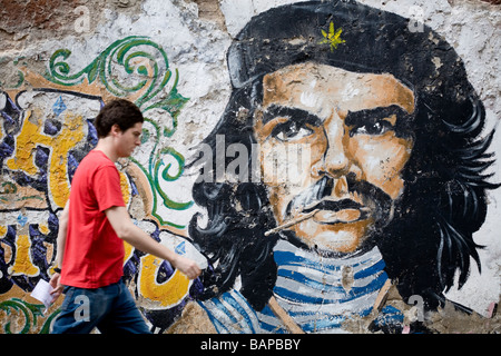 Un uomo che cammina in una strada di San Telmo quartiere con Che Guevara ritratto dipinto su una parete dietro, Buenos Aires, Argentina Foto Stock