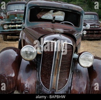 Vecchie automobili arrugginite nella pioggia a junkyard cercando triste Foto Stock