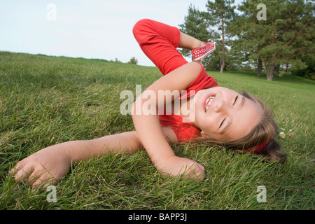 6 anno vecchia ragazza rotolamento su erba, Winnipeg, Manitoba, Canada Foto Stock