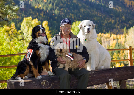 60 ish uomo con il suo sostegno emotivo cani includente un Bovaro del Bernese e un grande Pirenei Foto Stock