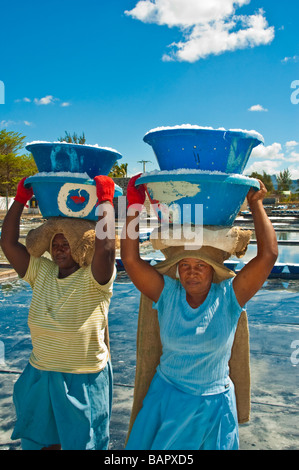 Produzione di sale, donna che trasportano il sale nella parte anteriore delle saline nei pressi di Tamarin Mauritius Foto Stock