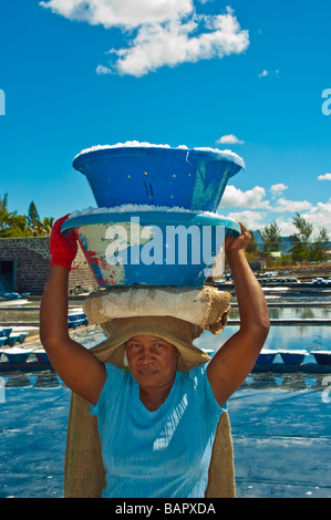 Produzione di sale, donna che trasportano il sale nella parte anteriore delle saline nei pressi di Tamarin Mauritius Foto Stock