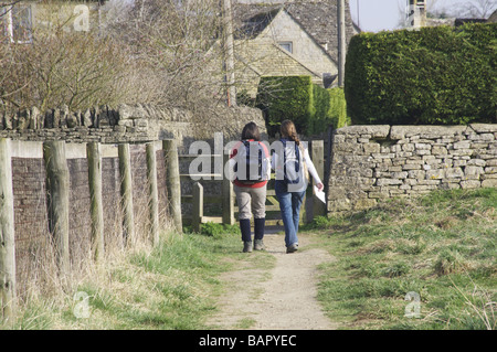 Due escursionisti con zaini sul modo Cotswold sentiero di avvicinamento inferiore villaggio slaugheter Foto Stock