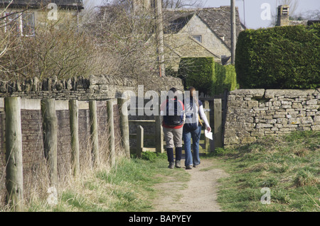 Due escursionisti con zaini sul modo Cotswold sentiero di avvicinamento inferiore villaggio slaugheter Foto Stock