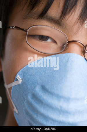Primo piano del giapponese ragazzo di dodici anni di indossare una maschera Foto Stock