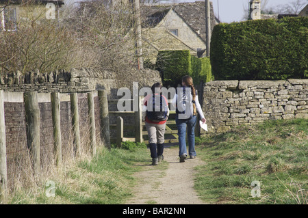 Due escursionisti con zaini sul modo Cotswold sentiero di avvicinamento inferiore villaggio slaugheter Foto Stock