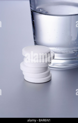 Ein Stapel aspirina Tabletten mit Wasserglas un mucchio di aspirina compresse con un vetro d'acqua Foto Stock