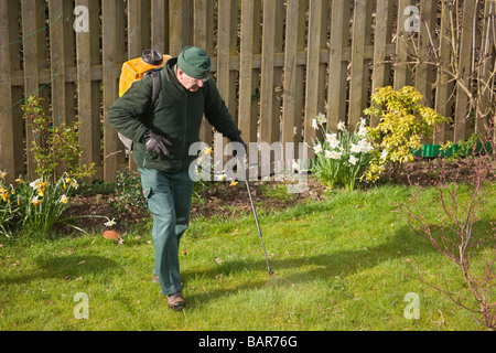 La Gran Bretagna UK Europa Uomo applicando prato primavera trattamento killer di erbacce nel giardino Foto Stock