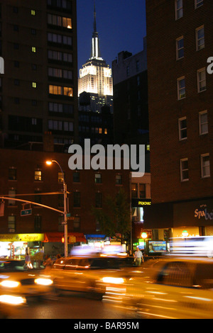 Giallo taxi e l'Empire State Building di notte New York City Foto Stock