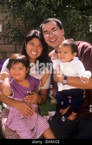 Asiatico-americano famiglia mamma papà Padre madre bambino ragazza ragazzo figlio figlia sorriso felice gruppo verticale Foto Stock