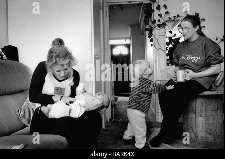 Una levatrice dal Royal Free Hospital controlla l'asciugatura del cordone ombelicale su un neonato come la madre beve il suo tè. Foto Stock