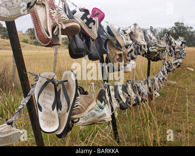 Perso e abbandonato i formatori, flip flop e scarpe appeso al filo spinato tasmania australia Foto Stock