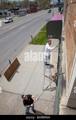 Volontari edificio di vernice come parte della comunità cleanup Foto Stock