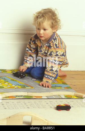 Ragazzo giocando con le automobili e treni di legno via Foto Stock