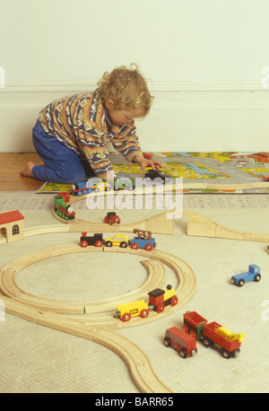 Ragazzo giocando con le automobili e treni di legno via Foto Stock